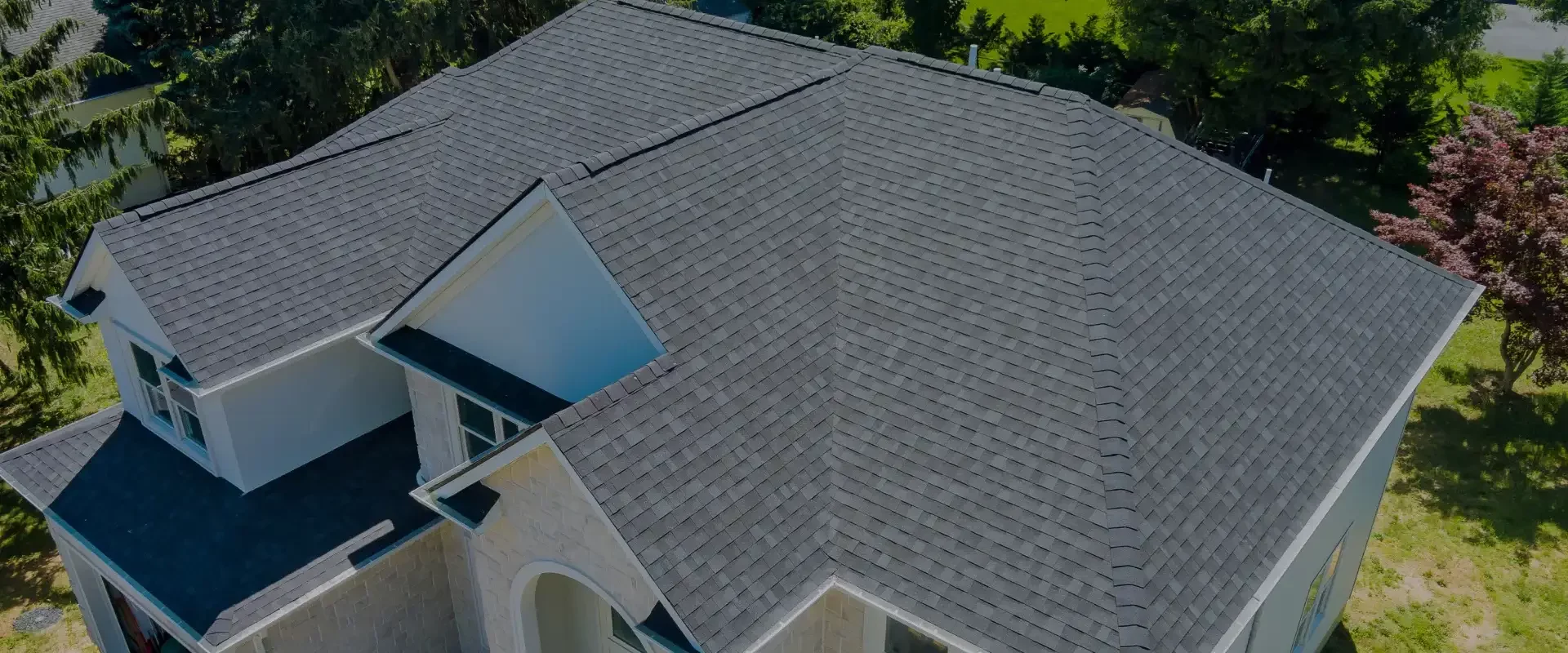 hero aerial view of a large house with an asphalt shingle roof